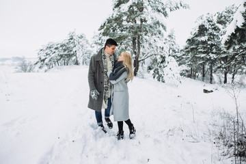 Happy loving couple walking in winter park enjoying snow