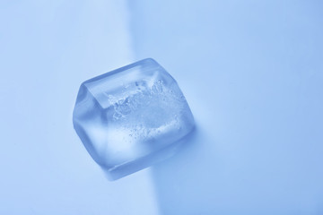 Obraz premium Ice cube on color mirror surface. Space for text