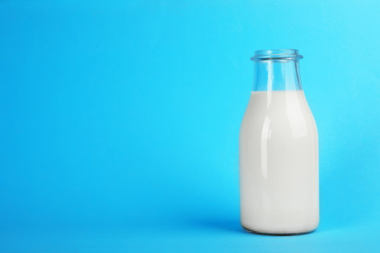 Glass bottle with fresh milk on color background. Space for text