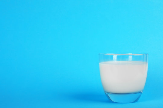 Glass with fresh milk on color background. Space for text