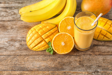 Tasty tropical drink with mango and fresh fruits on wooden table