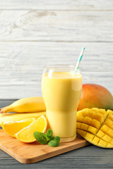 Tasty tropical drink with mango and fresh fruits on wooden table. Space for text