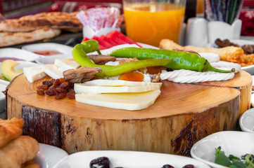 Cheese plate: Emmental, Camembert cheese, blue cheese, bread sticks, walnuts, hazelnuts, honey, grapes on wooden table