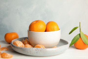 Plate and bowl with ripe tangerines on table