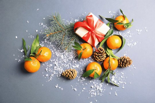 Christmas composition with ripe tangerines and gift box on grey background, flat lay