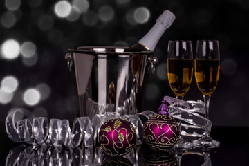 Two glasses with champagne, bottle and Christmas ornaments