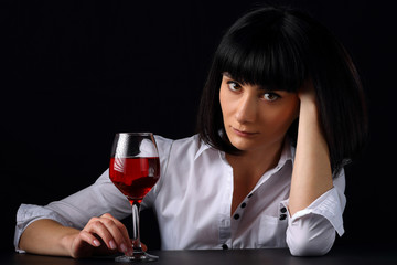 Beautiful girl with a glass of red wine on a dark background