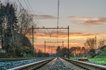 Fototapeta na wymiar Low-angle perspective image of railway line in the Dutch province of Limburg against a beautiful sunset sky
