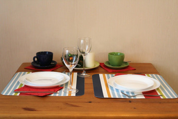 The holiday table is laid on two persons New Year's interior, two glasses, two cups for coffee, two plates