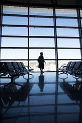 Young woman in the airport, looking through the window at planes