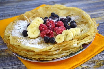 Delicious hot pancakes with fresh fruit on wooden background.