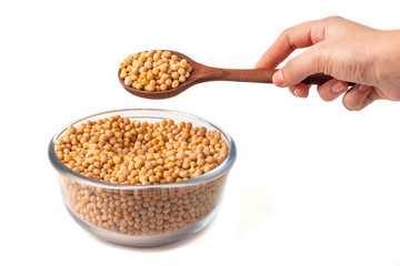spoon in hand with yellow peas on white background. Peas in glass bowl