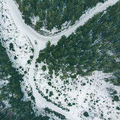 overhead view of suv car in snowed winter forest.