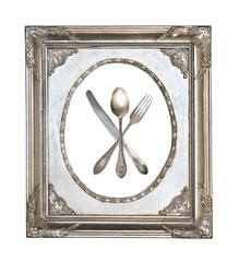 Vintage crossed spoon, fork and knife in silver openwork frame isolated on white background
