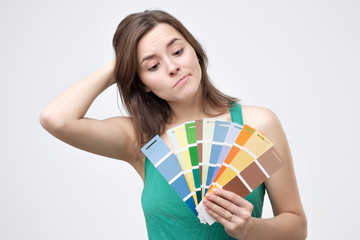 Attractive woman in green t-shirt chooses a color scheme. Difficult choice during home renovation