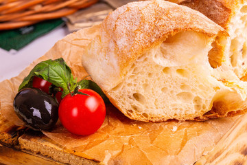 White loaf with olives and tomatoes on paper