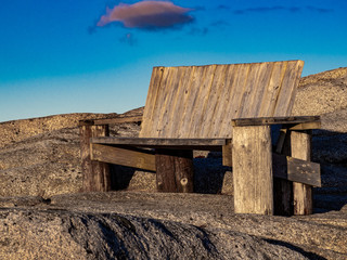 Wooden bench overlooking ocean at Peggy's Cove at sunset during winter, waves, storm, cold, 