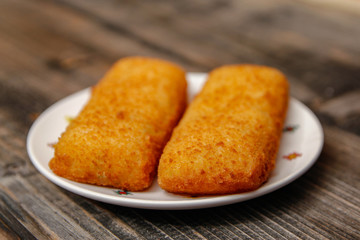Crispy breaded fried hake fish fillet on old wooden table