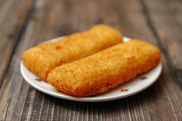 Crispy breaded fried hake fish fillet on old wooden table