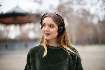 Portrait of smiling female listening to music in headphones in park