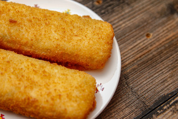 Crispy breaded fried hake fish fillet on old wooden table