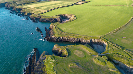 Rocky shore with green grass bordered by the ocean.