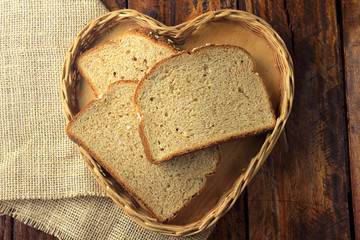 Organic sliced wholemeal bread, made from oats and flax seeds inside shape heart basket. Healthy diet