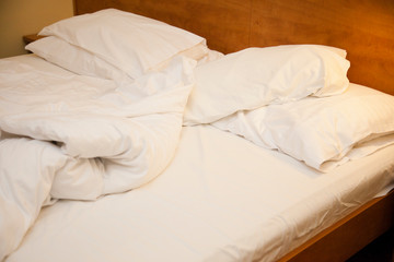 Simple double bed. Unmade bed. White cotton bed in hotel