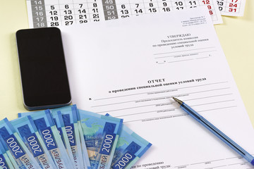 The inscription in Russian "Report on the special assessment of working conditions." Payment for special assessment. Pen and smartphone