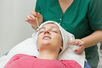 Face skin care. Beautician applying beauty oil mask on face using brush In spa salon