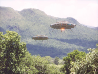 Two unidentified flying objects over a forest with trees and mountains behind. © ktsdesign