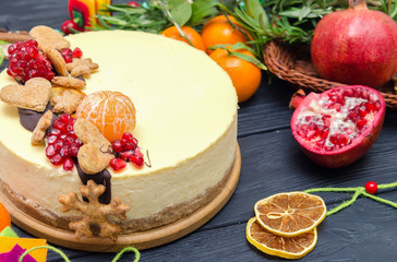 Homemade Christmas cheesecake on black wooden bacground decorated by orange, cookies, pomegranate, rosemary. Moist and smooth classic baked New York cheesecake.
