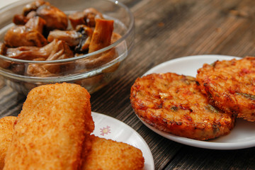 Crispy breaded fried fish fillet, vegetarian burger made from various type of vegetables and grilled champignons mushroom on old wooden table
