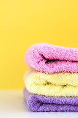 three multi-colored Terry towels have a yellow wall on white background