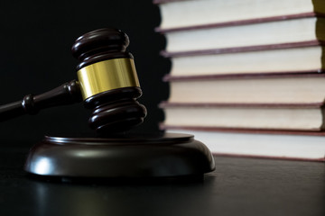 Judge gavel beside pile of books on wooden background