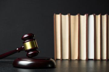 Judge gavel beside pile of books on wooden background