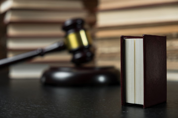 Judge gavel beside pile of books on wooden background