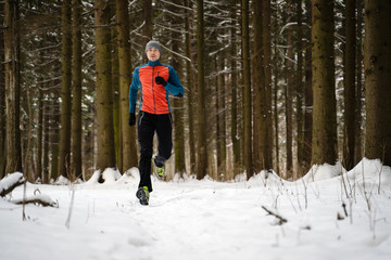 Photo of running athlete among trees in winter forest