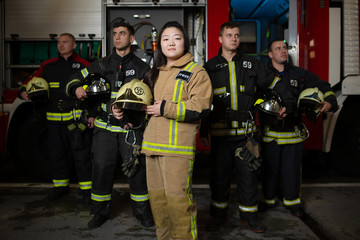 Image of four young male and female firefighters on background of fire truck