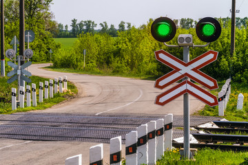 Railway traffic lights with a green signal. Railway and road crossing. Permissive Motion signal.