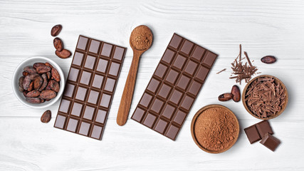 Chocolate bars with cocoa beans and bowl of chocolate chips and cacao powder for confectionery