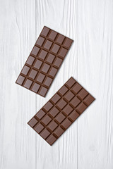 Top view on tasty chocolate bars on white wooden background