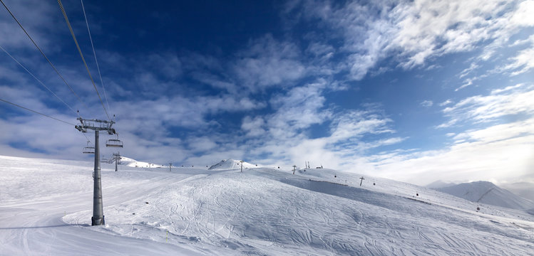 Ski slope, chair-lift on ski resort and blue sky with sunlight clouds