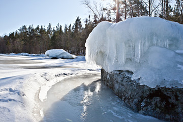 .Ice floe with icicles on the shore of Lake Ladoga on the edge of the forest