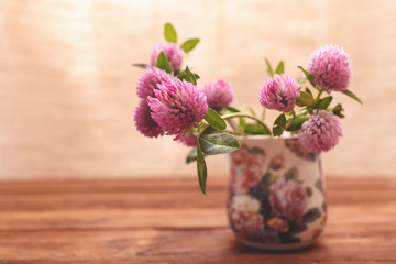 Clover flowers on wooden background. Beautiful purple wild flower. Medicinal herb. Close-up of red clover flowers in the lighting Studio