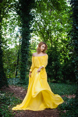 Fototapeta premium A girl in a long yellow dress is dancing in the open air