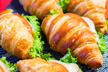 Close up fresh croissants with salad, ham and cheese on table