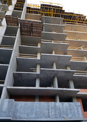 Construction of a new house, bottom view. Gray high-rise building, open balconies. The structure of a residential complex in the city. Unfinished house with open balconies