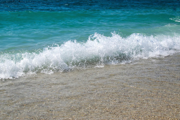 Beautiful sandy beach, sunny summer day. Sea waves with foam close up