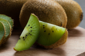 Fresh ripe sliced kiwi fruit, whole half and piece organic juicy kiwi fruits on wooden background
